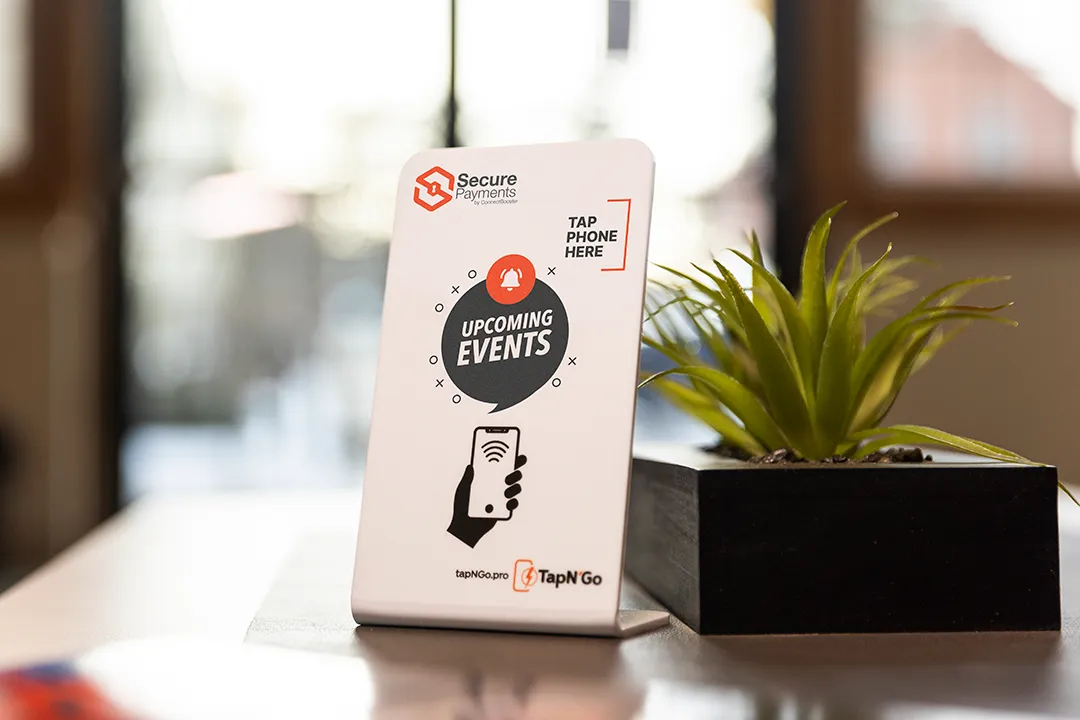 A clean table with a sleek white TapN'Go stand next to a small decorative plant