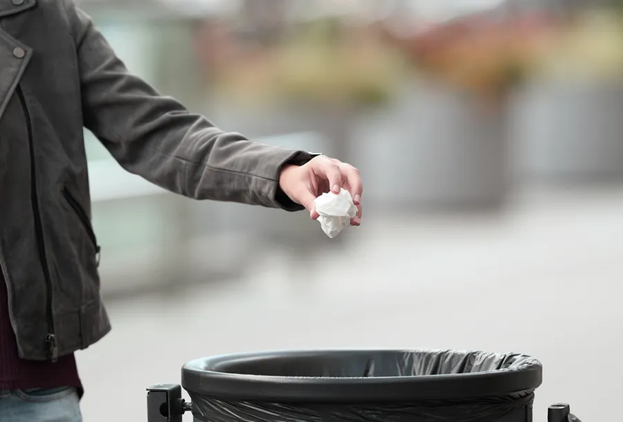 Attendee throwing handout in the trash bin